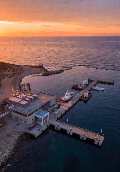 Aerial view of hushmovari.life's coastal service facility and testing dock at sunset